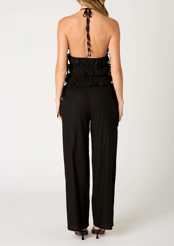 A person wearing a pair of relaxed black wide leg trousers with side tie detail at waist.