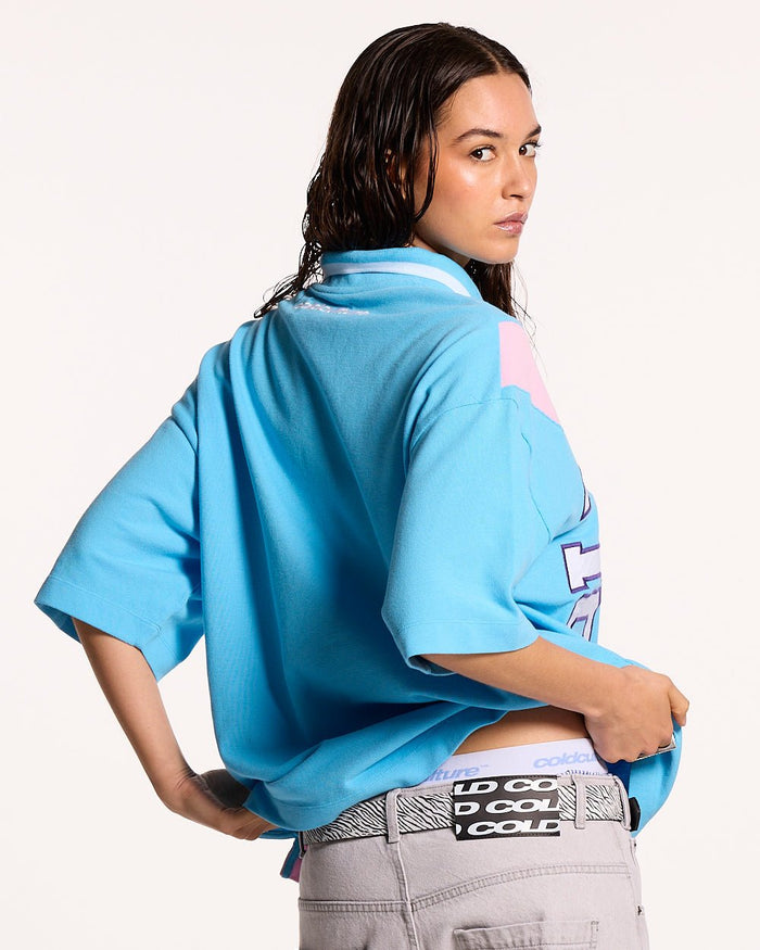 COCKY POLO BLUE - blue graphic print polo shirt, back view on female model - Cold Culture #woman