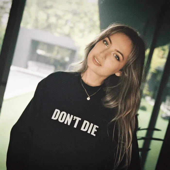 Woman wearing black Don't Die sweatshirt standing outdoors