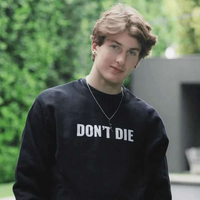 Man wearing black Don't Die sweatshirt outdoors with green background