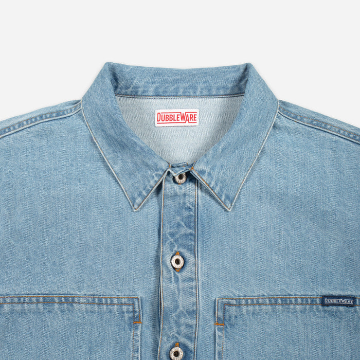 Close-up of a light blue denim button-up shirt collar and chest area, showing the Doubleware brand label inside the neck and a small Doubleware tag on the chest pocket.