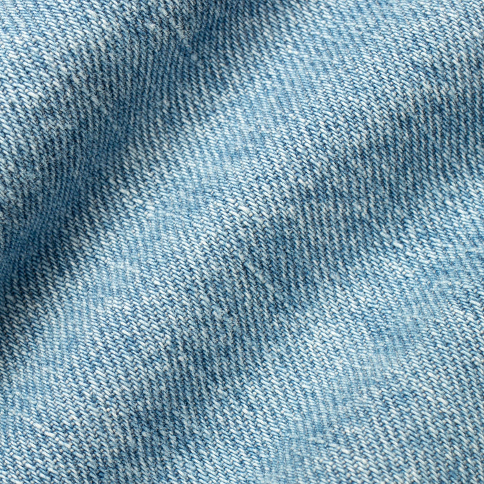 A close-up of light blue denim fabric with a visible twill weave texture and soft folds.