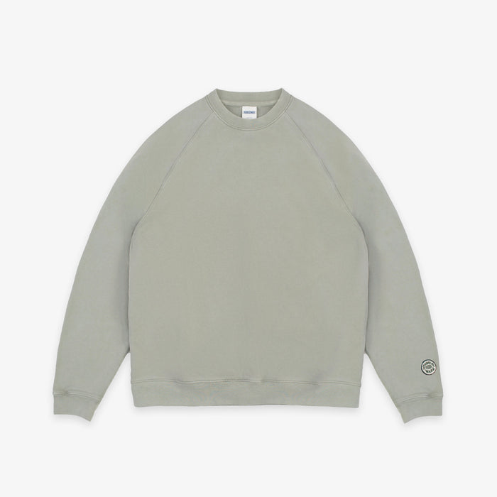 A light sage green crewneck sweatshirt with raglan sleeves, laid flat against a clean white background.
