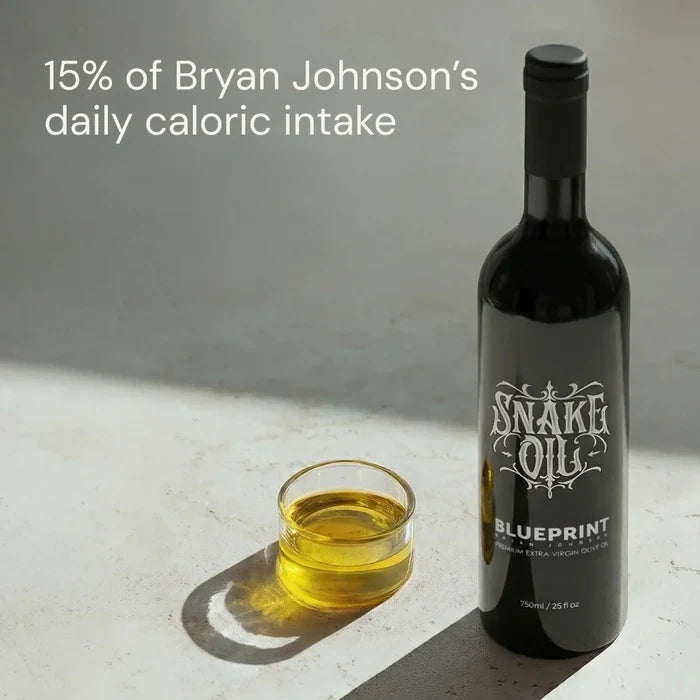 Bottle of 'Snake Oil Blueprint' with a glass of oil on a light surface.