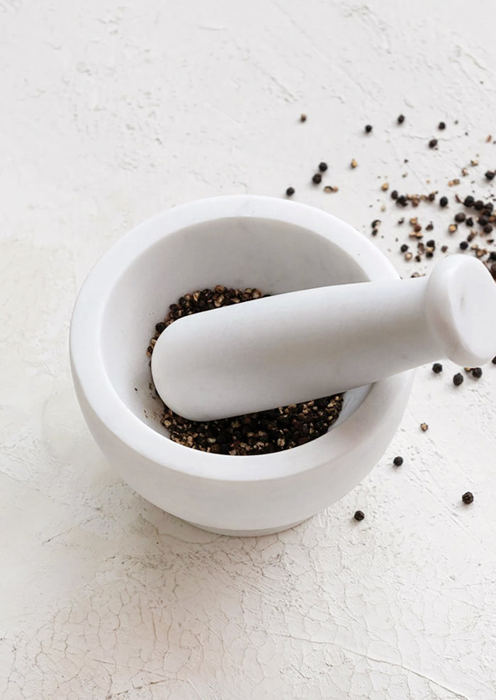 A mortar and pestle in solid white marble.