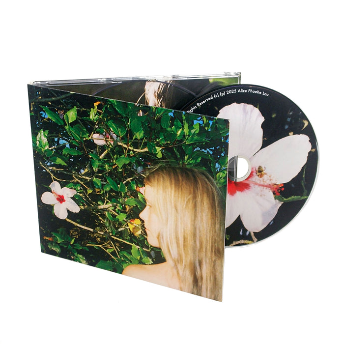A CD and its case featuring a cover photo of a person with long blond hair surrounded by green leaves and large white flowers with pink centers, evoking the serene mystique of a Mind Reader. The CD shows a close-up of one of the flowers with a bee on it.