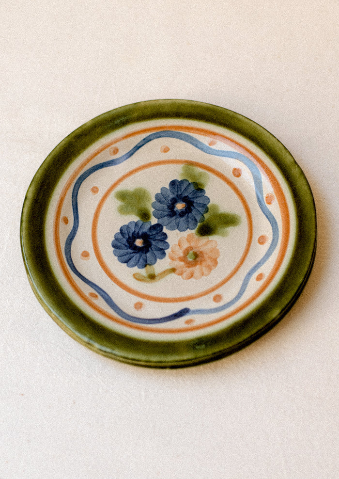 A pair of floral and squiggle painted plates in green, blue and orange.