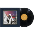 A vinyl record next to its cover, which features a classical statue among rocky mountains with a crescent moon in a colorful dusk sky, as distant galaxies shimmer above the serene landscape.