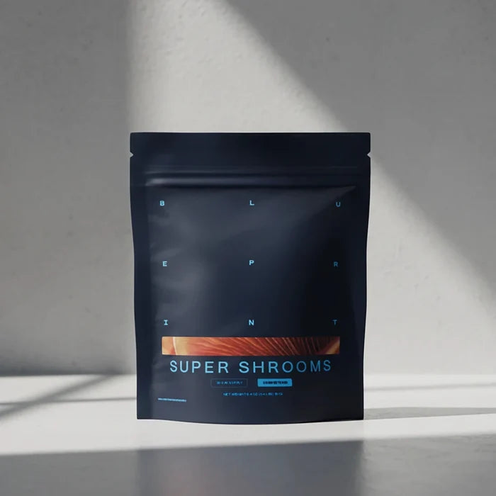 Black package labeled 'Super Shrooms' on a gray surface with a light gray background