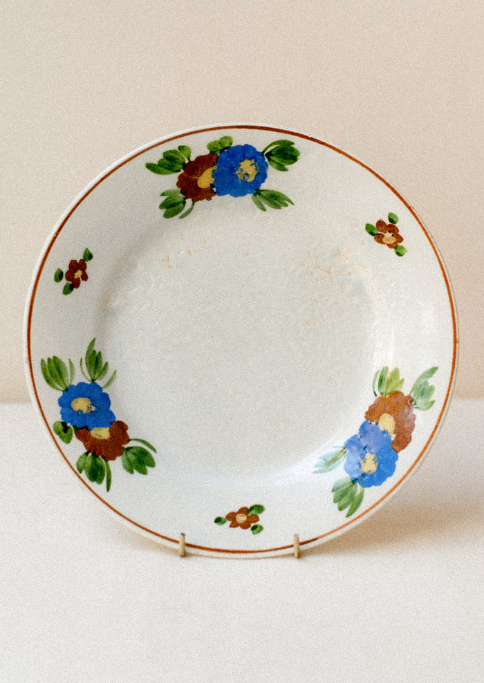 A ceramic plate with blue and brown painted floral pattern.
